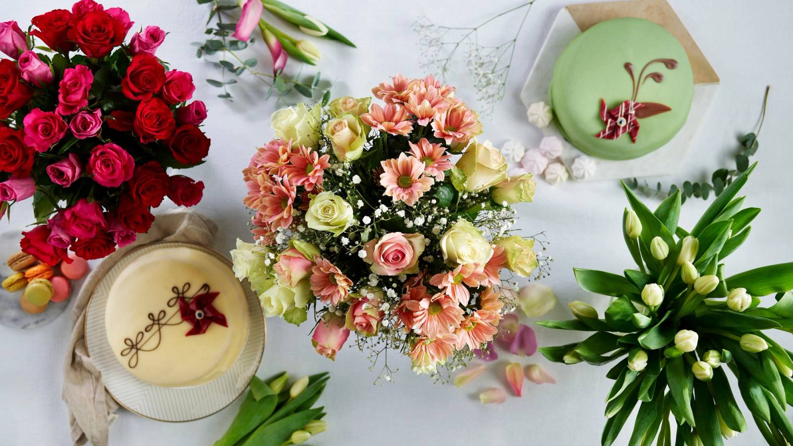 Langt, smalt dekket bord med blomsterarrangementer og lys, sett ovenfra.