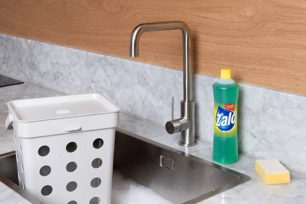 Oppvaskkummens kant med en Zalo-flaske og en oppvaskbøtte på kjøkkenet