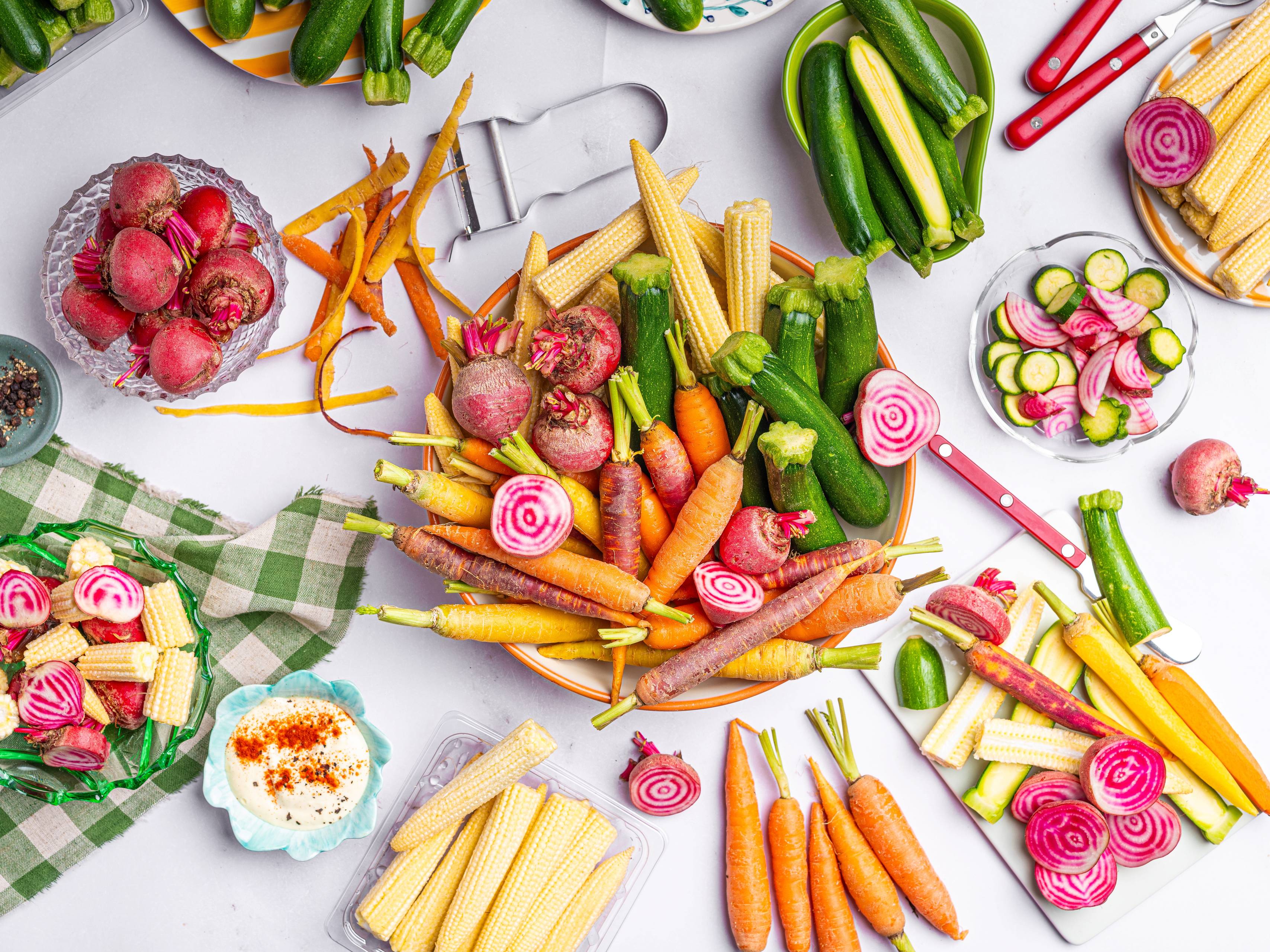 Fargerike grønnsaker og mini plakat med bilder av ulike grønnsaker på et bord.