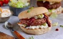 Hamburger med coleslaw og ketchup i et hamburgerbrød, med en skje med coleslaw ved siden av.