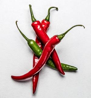 Fargerike chilipepper i rødt og grønt ligger på en lys bakgrunn.