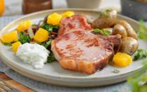 Stekt kotelett med poteter, grønnsaker og saus på en tallerken, klar for servering.