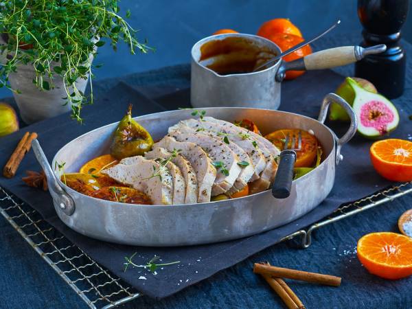 Saftig kalkunfilet skåret i skiver og servert med grønnsaker og saus på en oval tallerken.