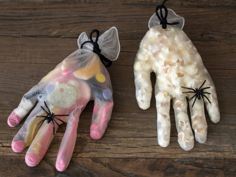 To håndputer, en med godteri og en med popcorn, plassert på en treoverflate.