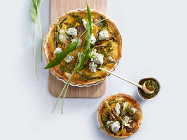 Chevre- og ramsløkspai med grønn løk og blåmuggost på en treplate, sett fra oven.