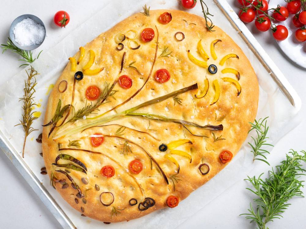 Focaccia med blomsterdekorasjon av cherrytomater, oliven og urter