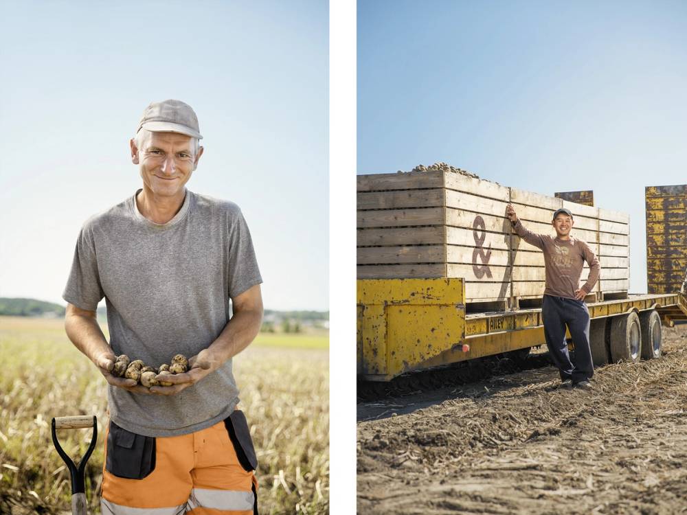 Person står i en åker med jord i hendene på venstre side og en annen person står ved en lastebil med store containere på høyre side.