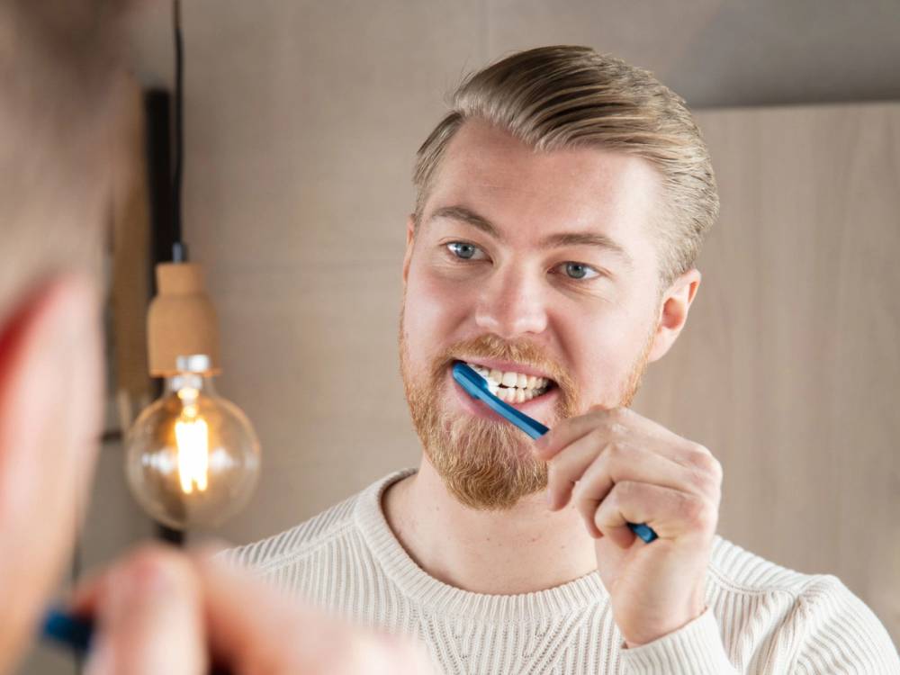 Person holder opp en papirplate foran ansiktet sitt i et rom med en lampe i bakgrunnen.