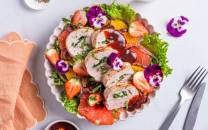 Svinefilet fylt med ost og spinat, servert på en tallerken med grønnsaker og blomsterdekorasjoner.