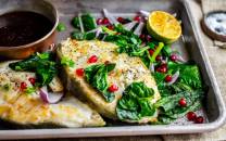 Stekt skrei med grønnsaker, sitron og granateple på et fat.