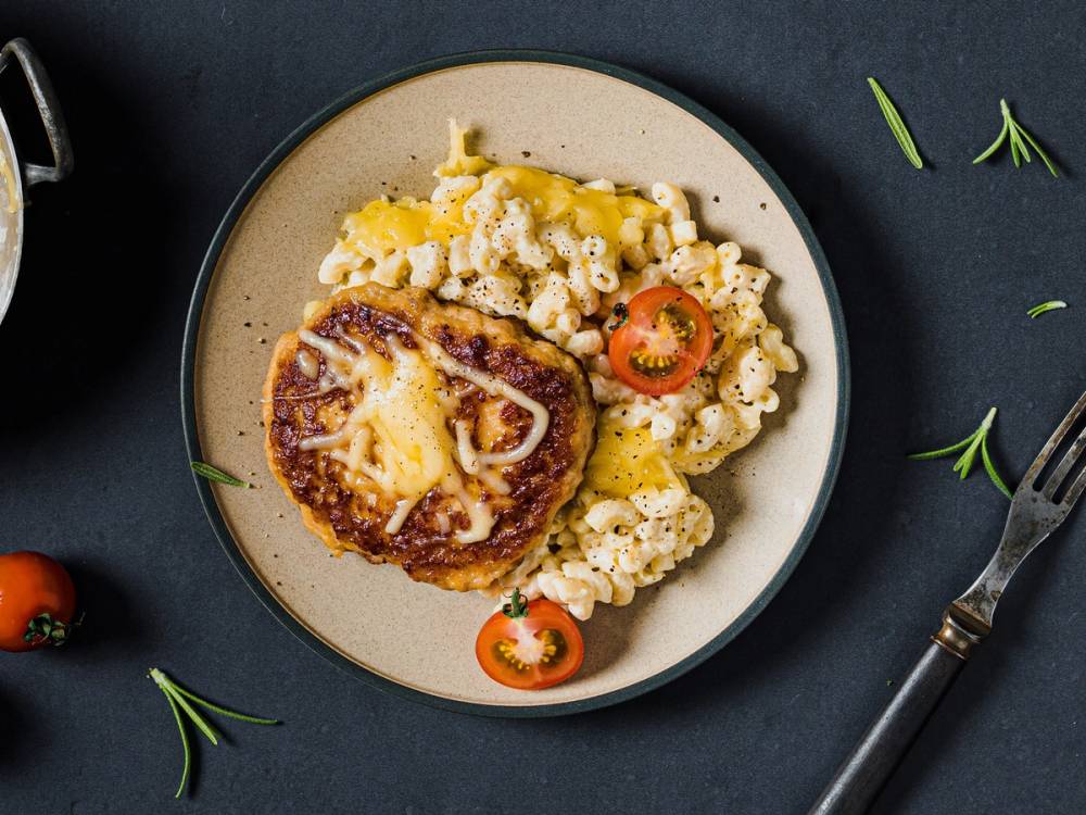 En tallerken med en baconburger og pasta med tomatskiver, ser ut til å være en menyrett.