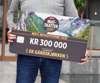 Person holder en stor sjekk med teksten: MENYs Matskattstipend 2020, kr 300 000, hovedstipend: Ek Gårdskjøkken.