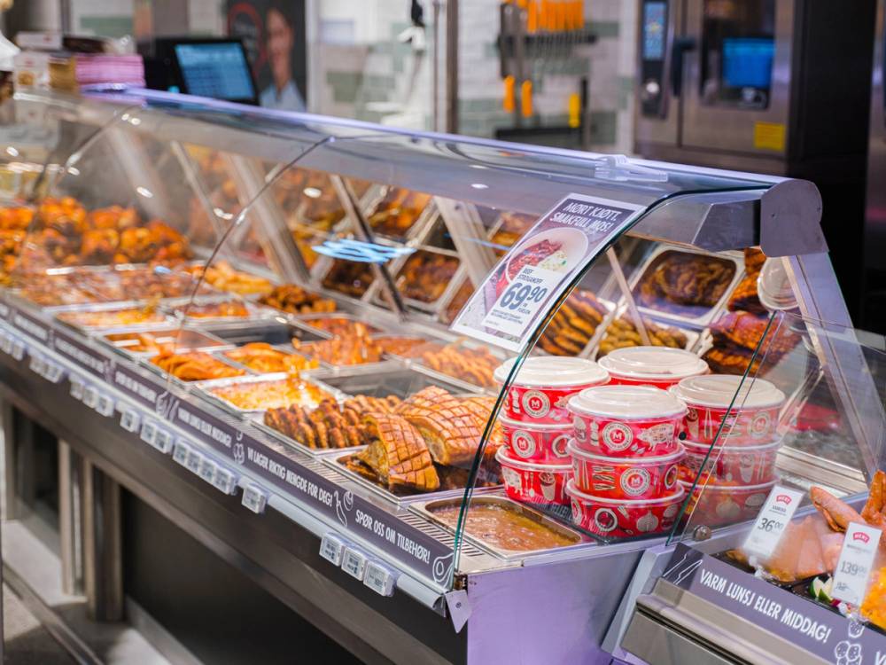 Ulike ferdigretter og pålegg i en kjøledisk på Meny i Oslo City, med priser og emballasje synlig.