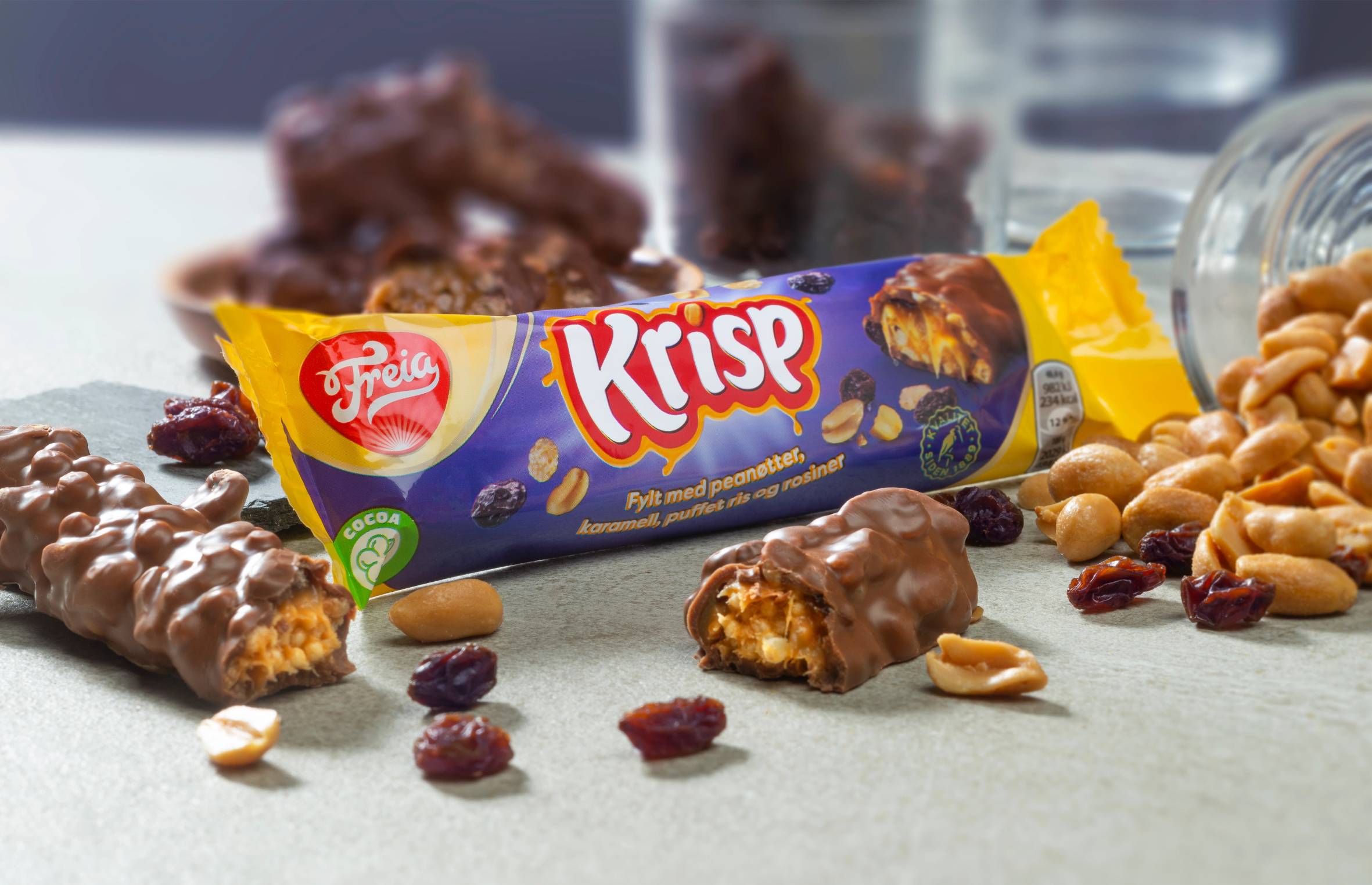 Krisp2 sjokoladebar omgitt av nøtter og tørket frukt på et bord