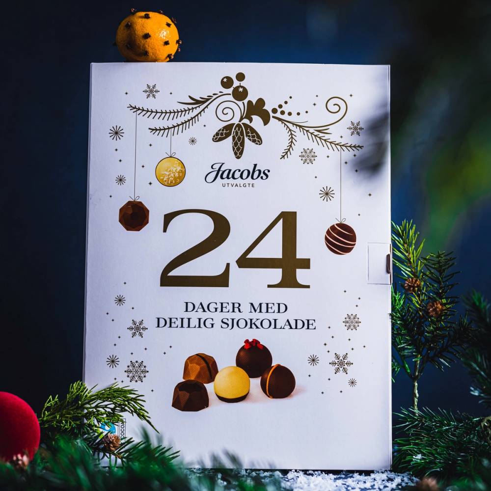 En kalender med tallene 24 og teksten 'Dager med deilig sjokolade' omgitt av juledekorasjoner og sjokoladekuler.