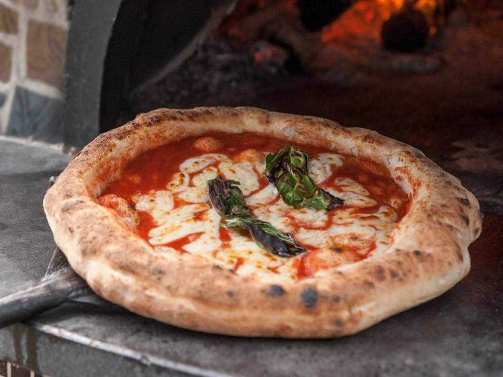 En pizza med kanthale og tomatsaus, med noen grønne urter på toppen, som er stekt i en ovn.