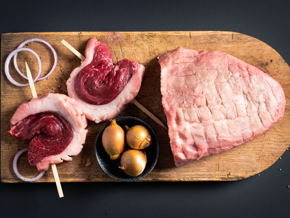 Ulike typer av kjøtt, inkludert angus culotte, ligger på et skjærebrett sammen med noen egg og kjøttspyd.