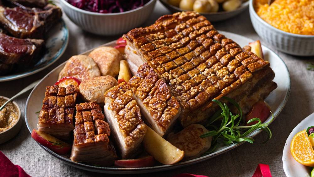 Julebord med ribbe, medisterkaker, rødkål og tilbehør på et dekket bord.