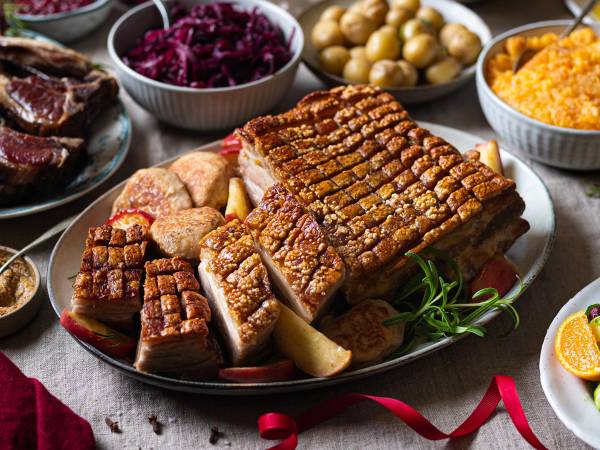 Julebord med ribbe, medisterkaker, rødkål og tilbehør på et dekket bord.