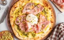 Pizza med mortadella, skinke og et speilegg på toppen, ser varm og innbydende ut.