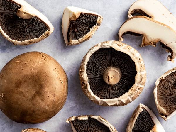 Ferske portobellobeter med noen som er skåret opp og andre hele, på en lys bakgrunn.