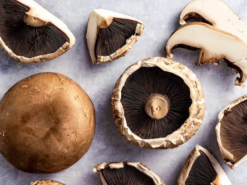 Ferske portobellobeter med noen som er skåret opp og andre hele, på en lys bakgrunn.
