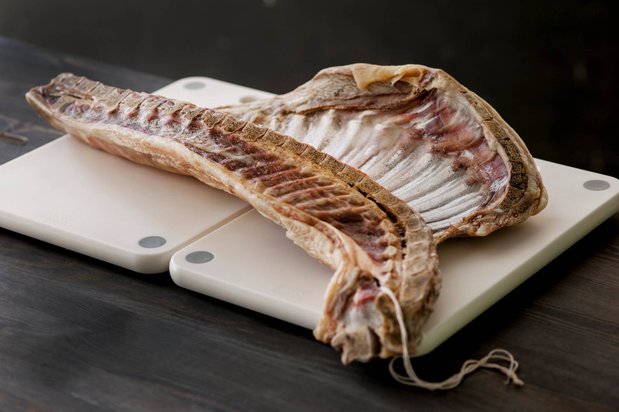 Rå fisk, sannsynligvis en torsk, ligger på en skjærefjøl klar til tilberedning.