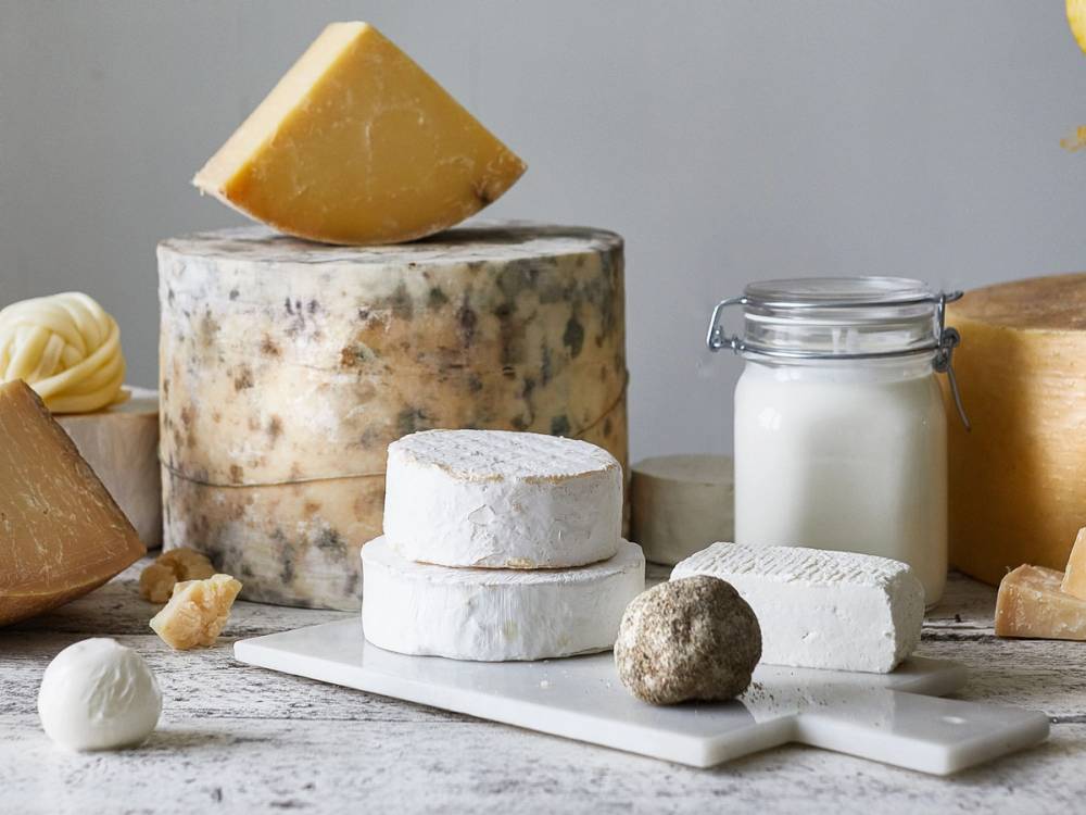 Et ostebord med ulike typer ost, en melkeflaske, og noen småkaker, satt opp på et bord.