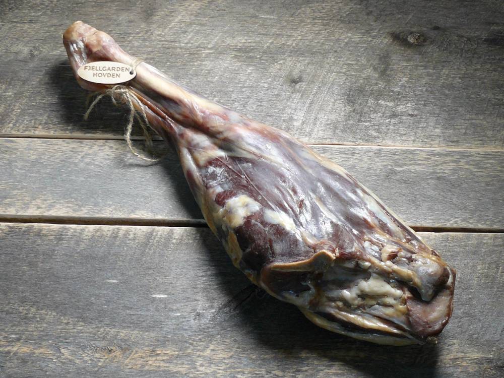 Et stykke tørket kjøtt eller spekemat lagt på en treflate.