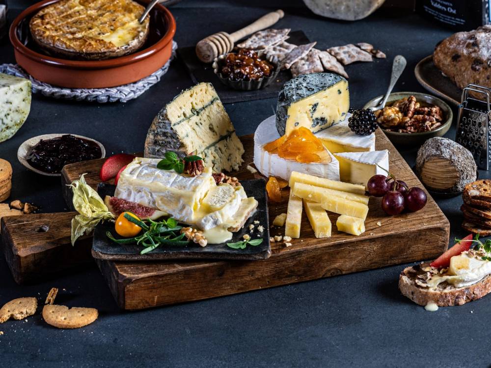 Et utvalg av oster, kjeks, frukt og syltetøy på et serveringsbrett, klar for helgekos.