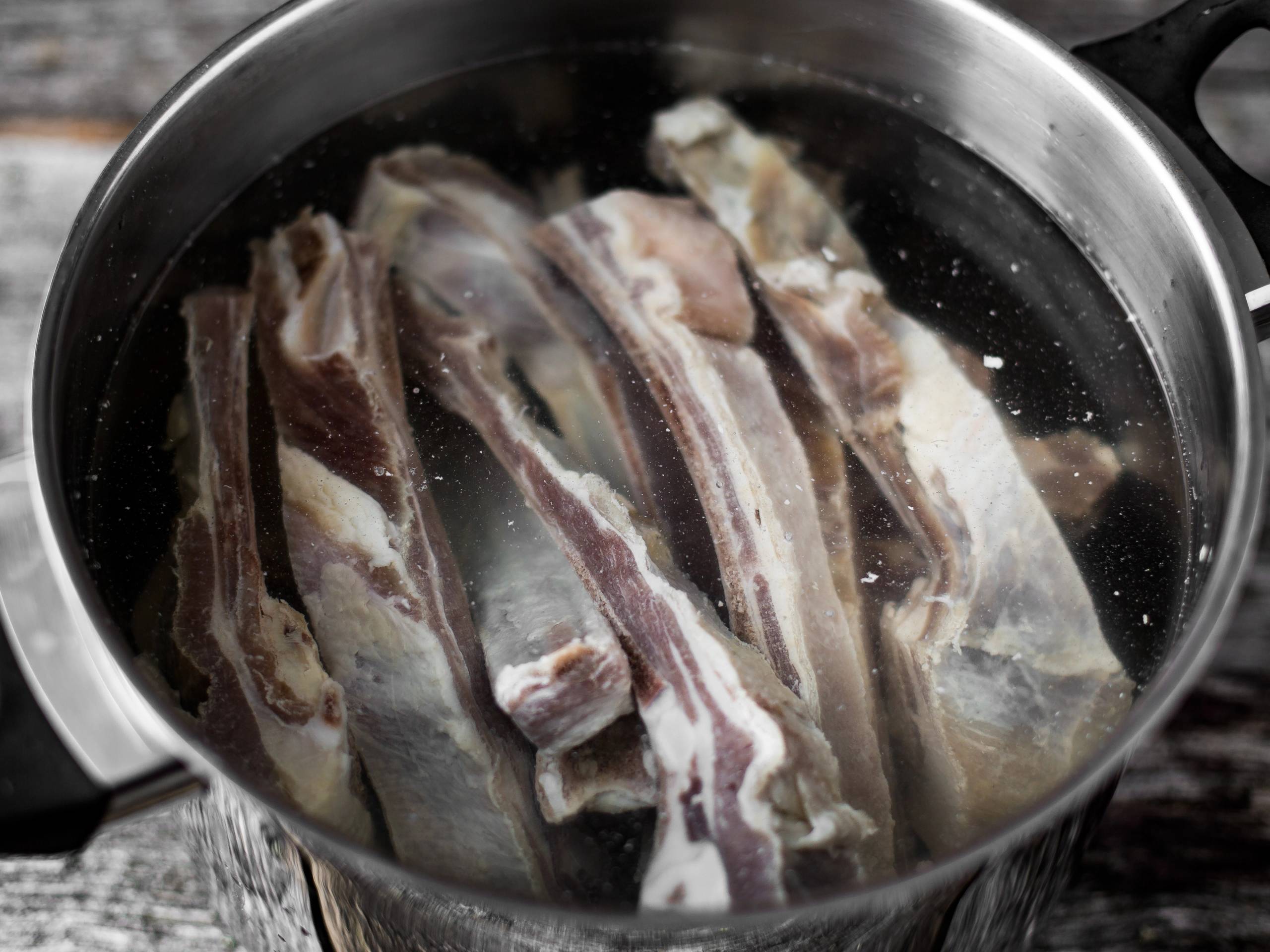 Pinnekjøtt som ligger i vann i en stor kjele før koking.