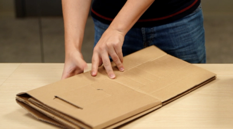 Person som pakker ut en stor pappeske på et bord.