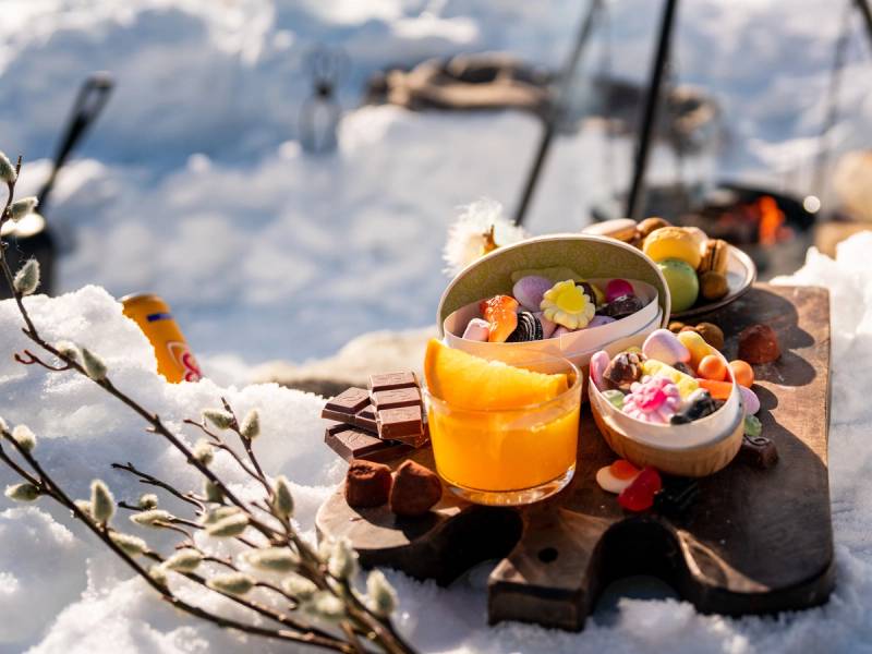 Påskegodt og blomster på et bord ved vannet med båter i bakgrunnen.