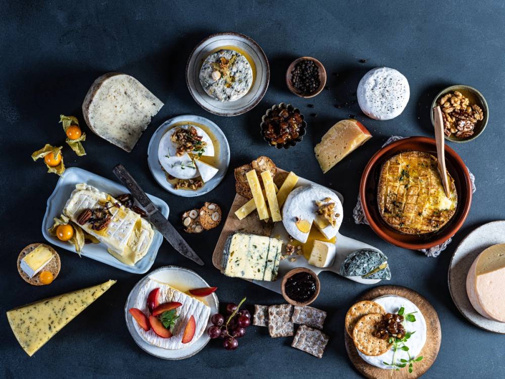 Et variert utvalg av oster, kjeks, frukt og tilbehør på et fat, egnet for ostefest eller tapas.