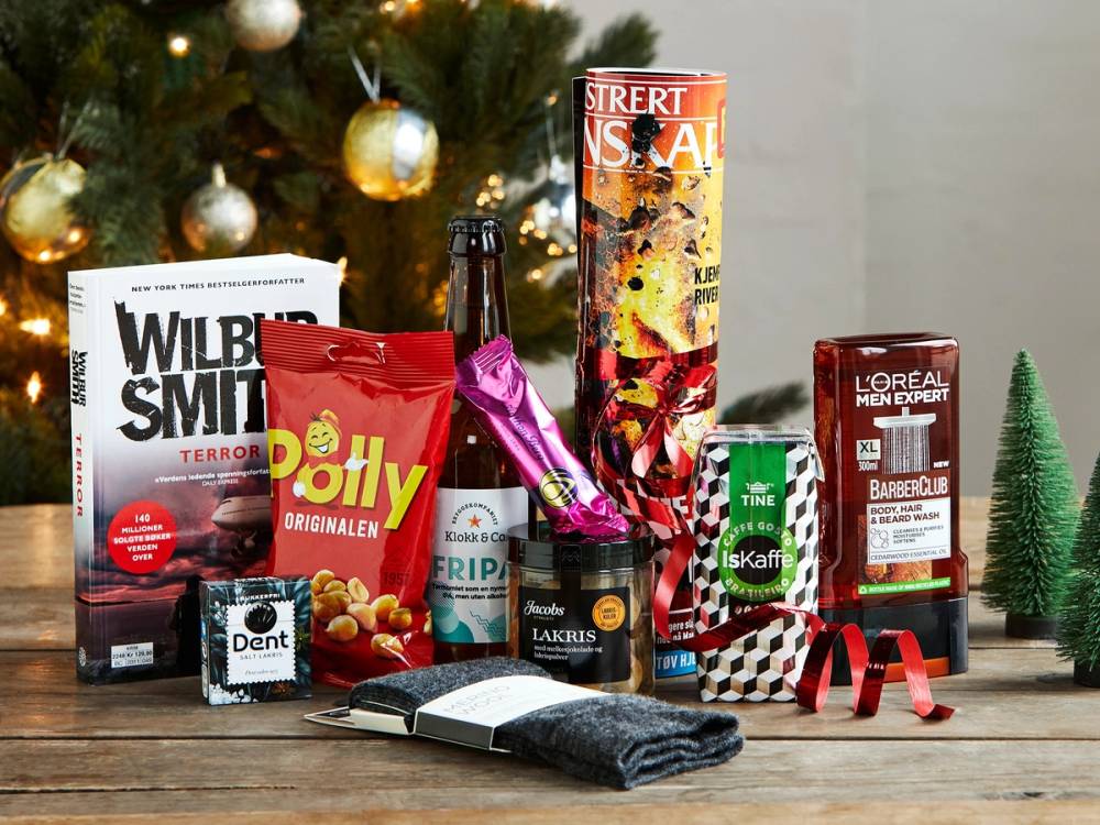 En julekalender med ulike produkter som sjokolade, kaffe og skjønnhetsprodukter plassert foran en julegran med pynt.