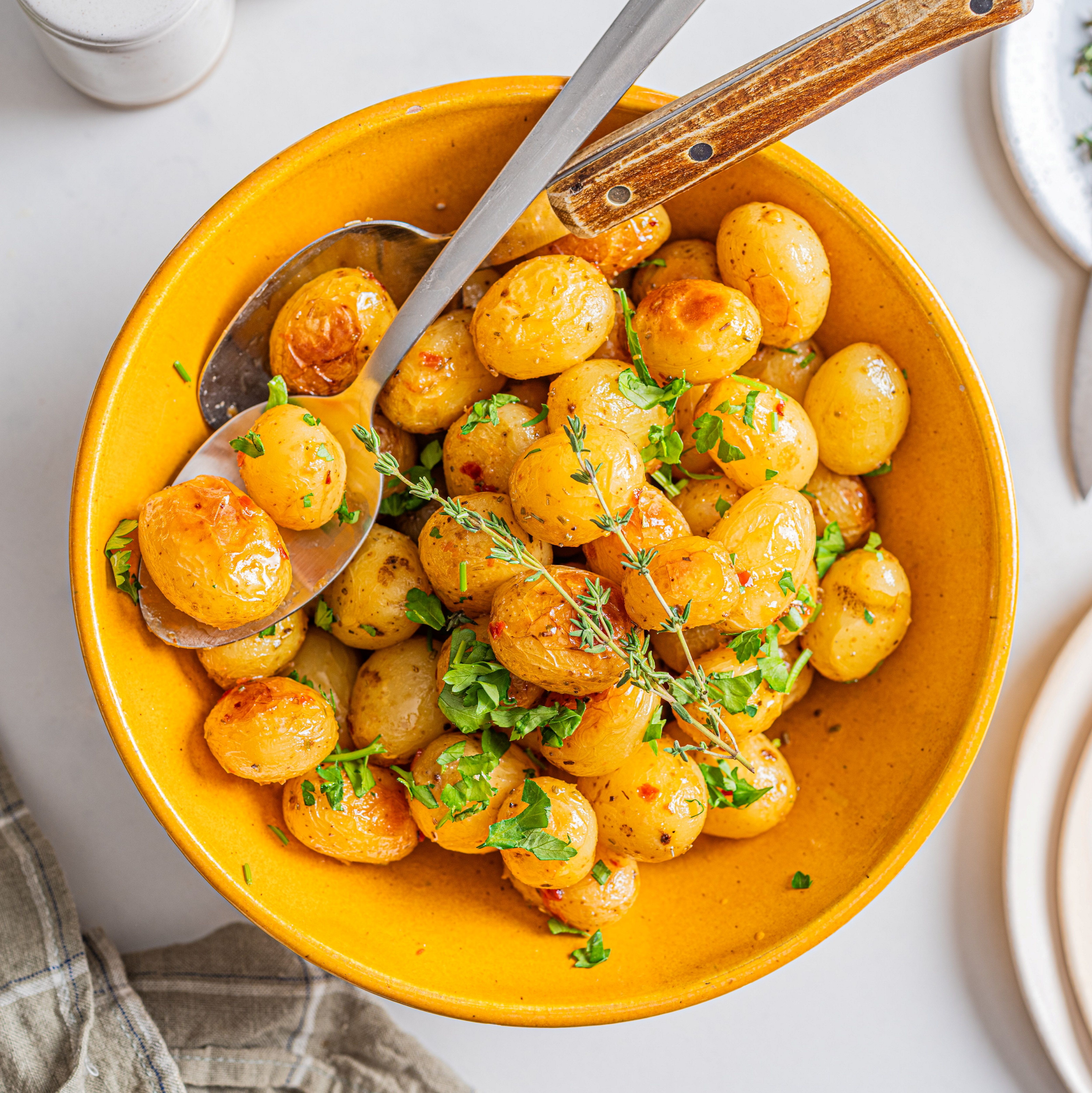 Perlepoteter med frisk grønn urter i en gul bolle, ser ut til å være kokt i kyllingkraft med sitron, på et hvitt bord.