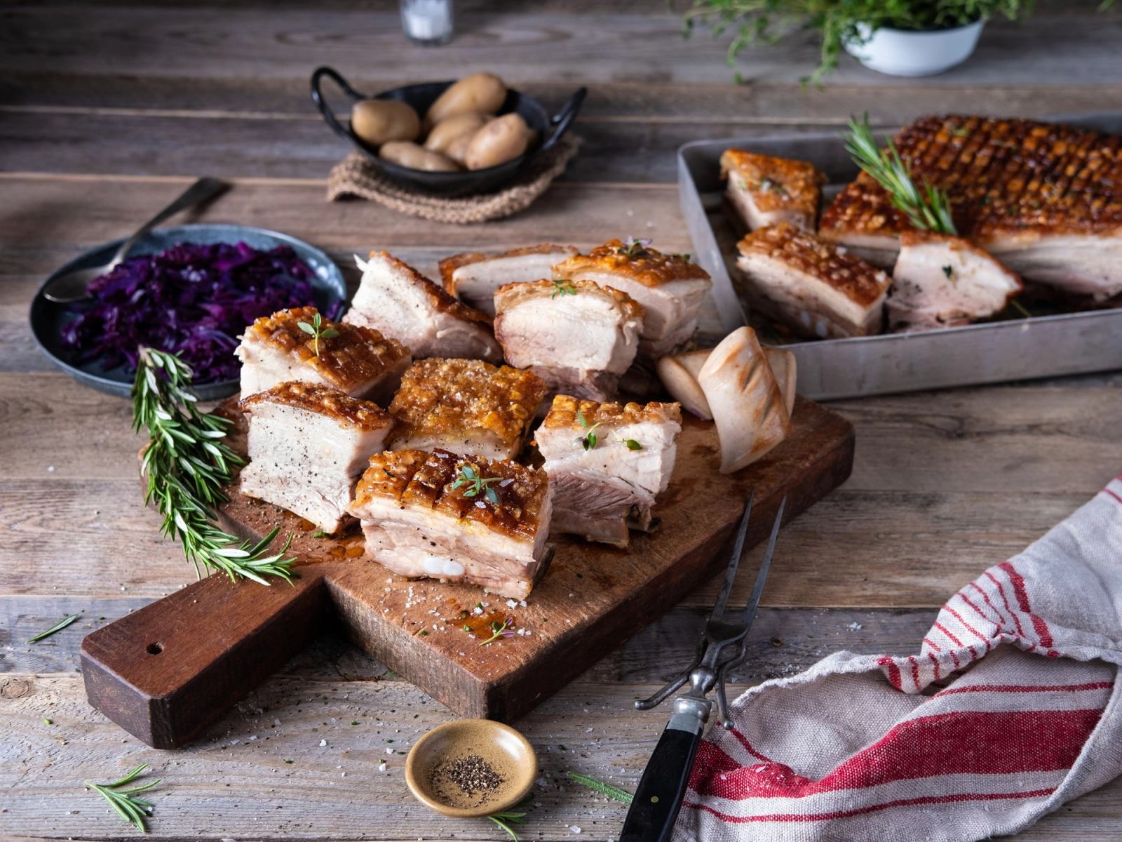 Ribbe med sprø svor på et skjærebrett med tilbehør som rosmarin og sennep, klar til jul.