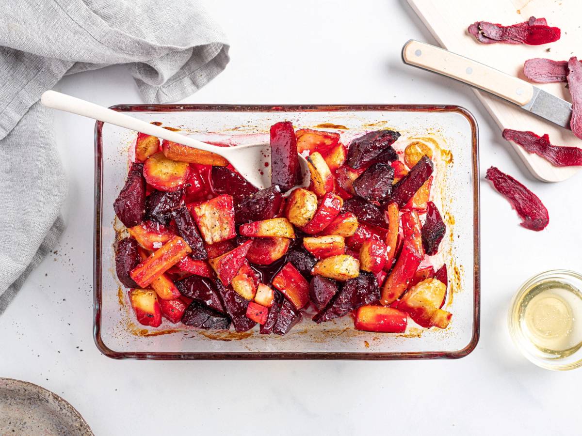 Honningglaserte rotgrønnsaker og beter i en ildfast form med en skje og noen skiver bete på siden