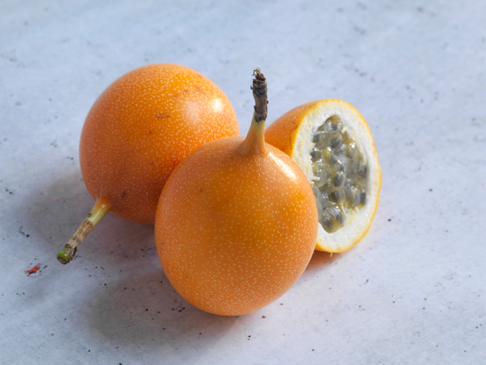 To granatepler, en hel og en halvert, ligger på en lys bakgrunn.