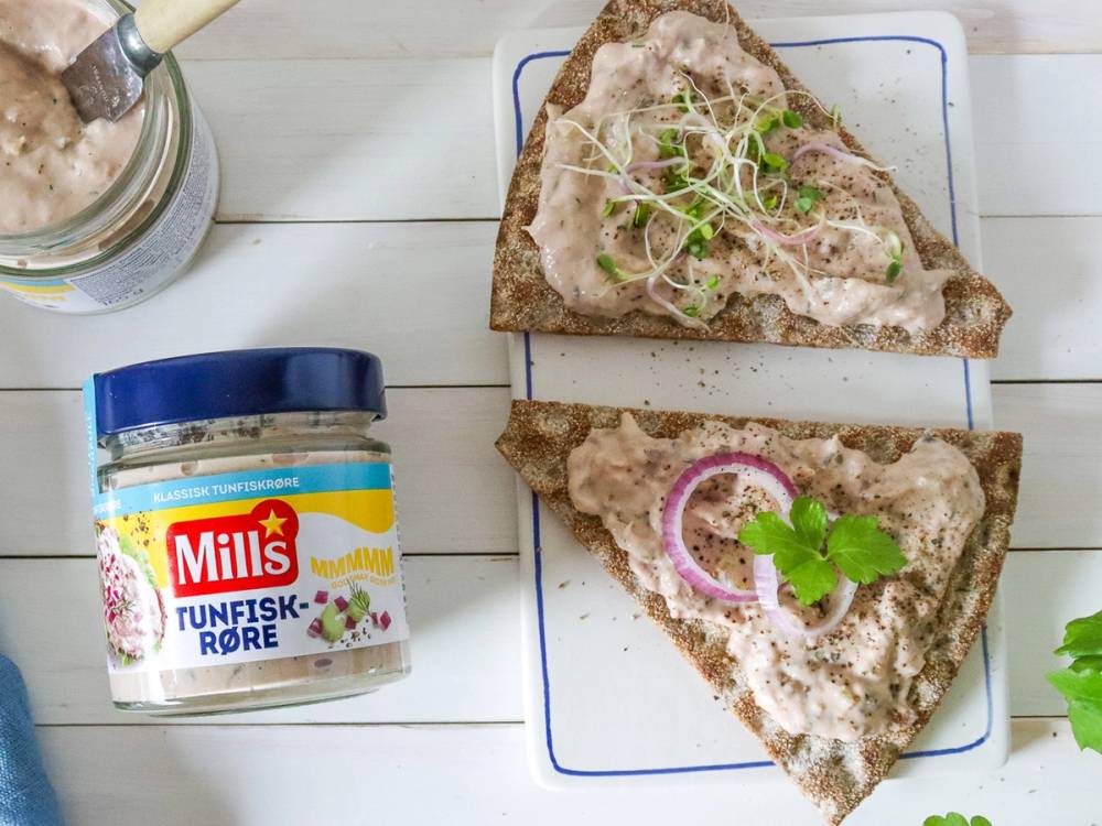 To knekkebrød med tunfisk og grønnsaker på en hvit tallerken, med en boks tunfisk i nærheten.