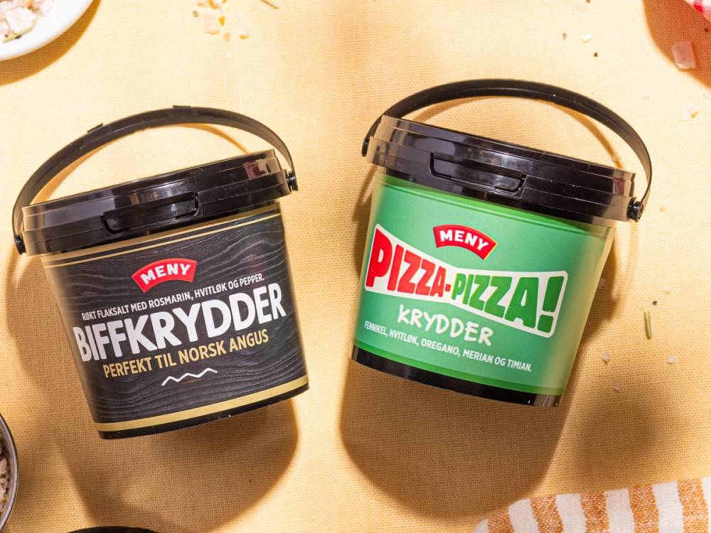 To krydderbokser med etiketter, en med biffkrydder og en med pizzakrydder, plassert på en overflate.