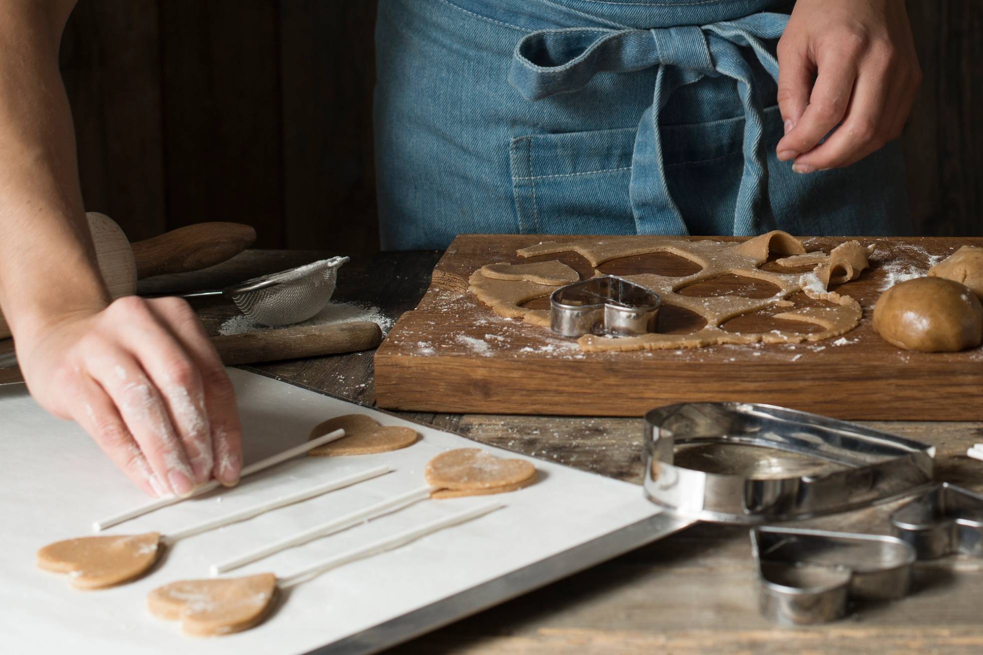 Personer lager pepperkaker med utstikkere på et kjøkkenbord.