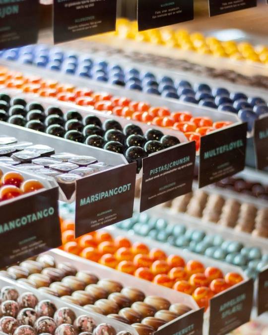 Ulike typer sjokoladedisker med fargede og ulike sjokoladekuler i en butikkhylle.