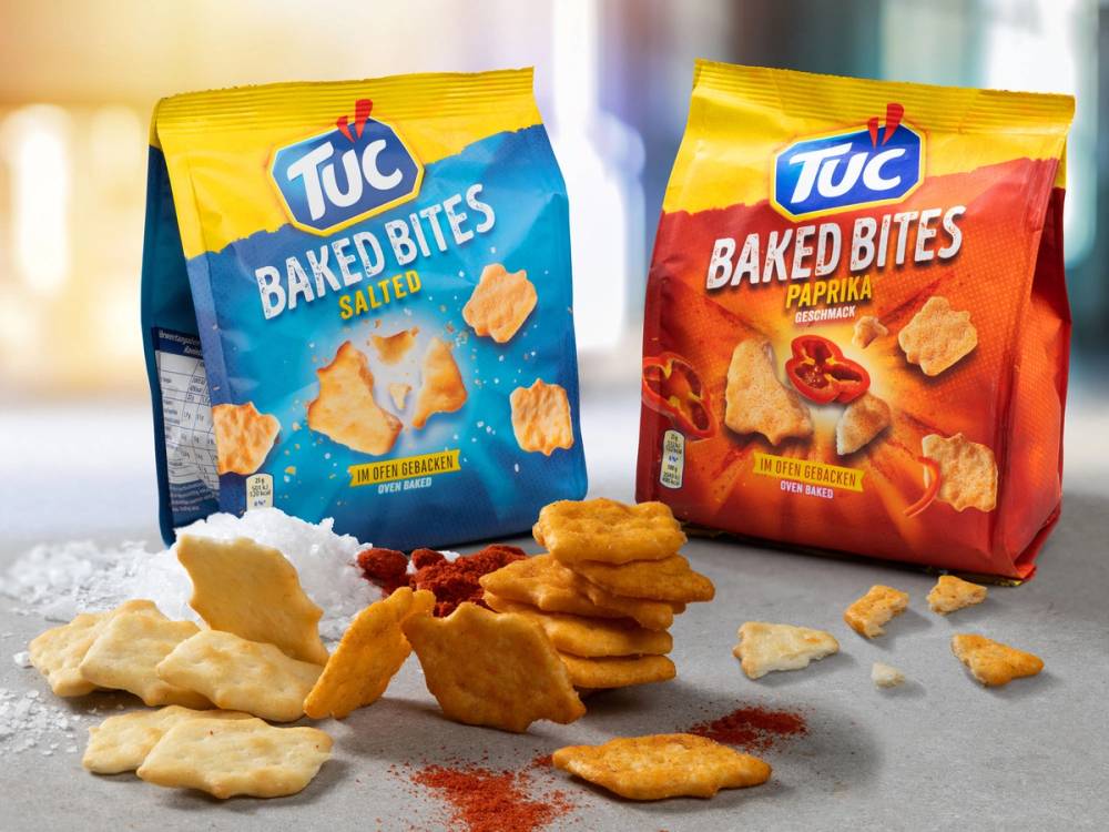 To poser med Tuc kjeks, en med saltet smak og en med paprika-smak, med noen kjeks og krydder rundt på bordet.