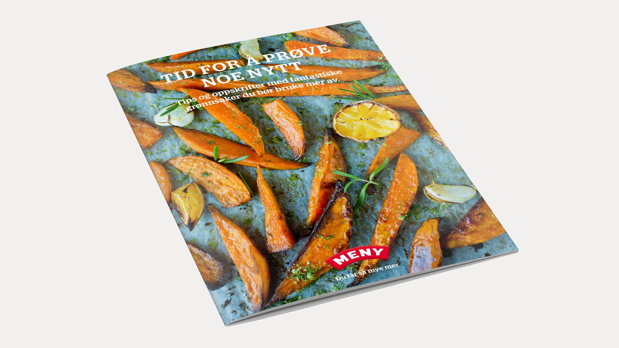 En kokebok med bilder av stekte gulrøtter og sitron, plassert på et bord.