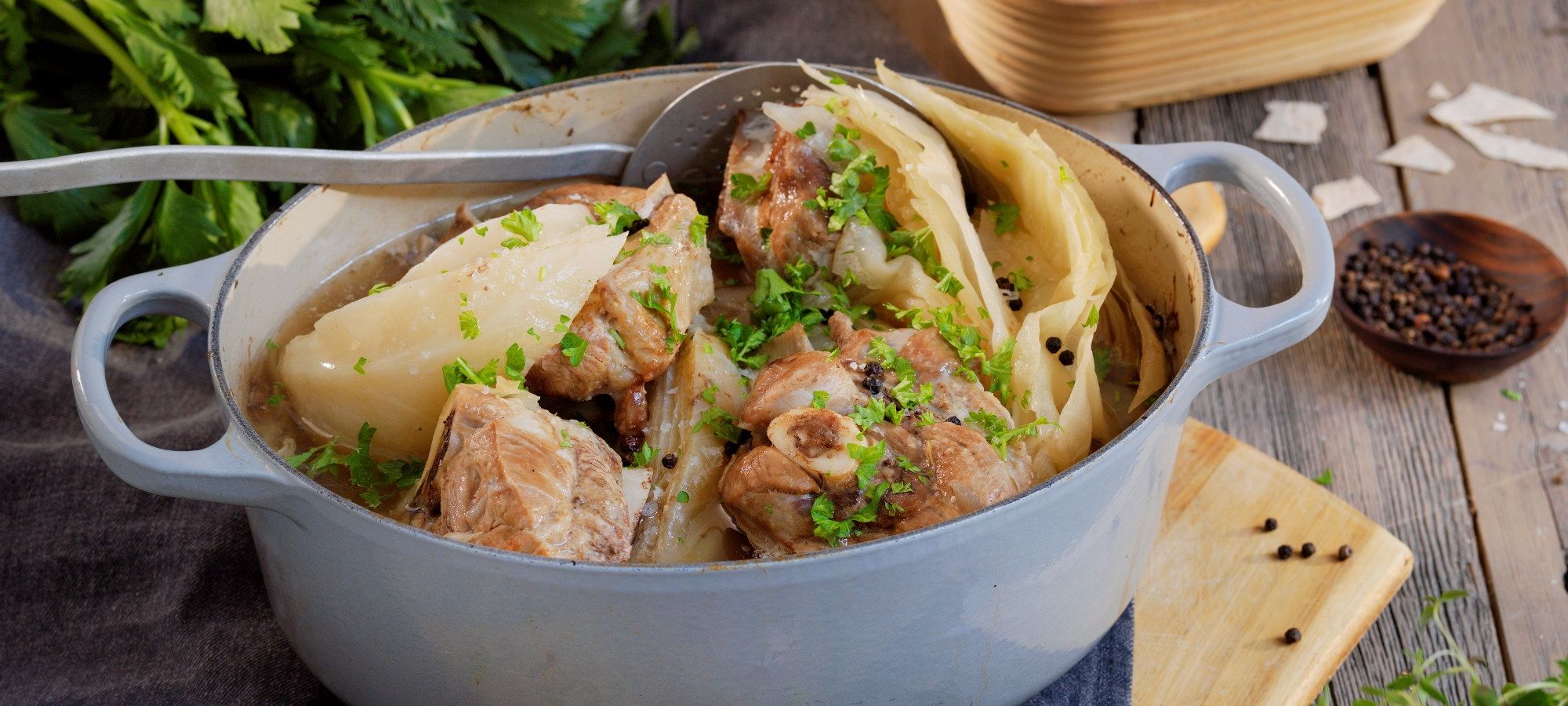 Fårikål i en oval gryte med hel kål, fårikålkjøtt og hele pepperkorn, klar til servering.