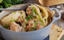 Fårikål i en oval gryte med hel kål, fårikålkjøtt og hele pepperkorn, klar til servering.