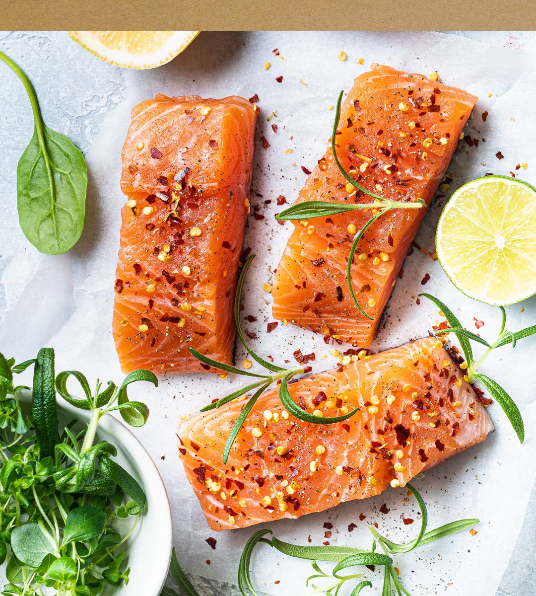 Tre laksefileter med sitronskiver og urter på en hvit bakgrunn, pyntet med pepper og grønne urter.