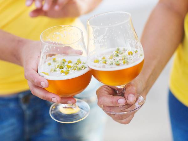 To personer skåler med øl i glass under en sommerlig anledning.