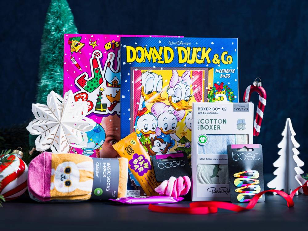 En samling med julegaver og leker, inkludert tegneserier, sokker og julepynt, på et mørkt bakgrunnsbilde.